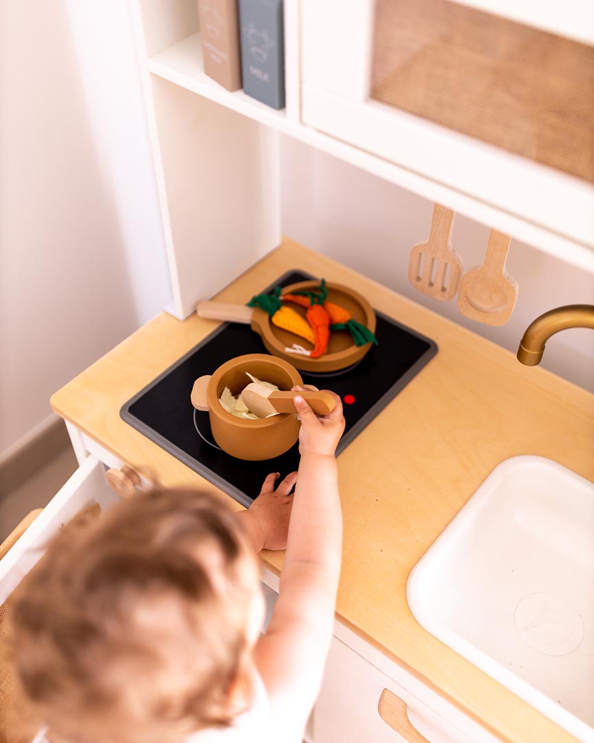 Cette image représente une petite fille faisant la cuisine dans sa cuisine Duktig Ikea.